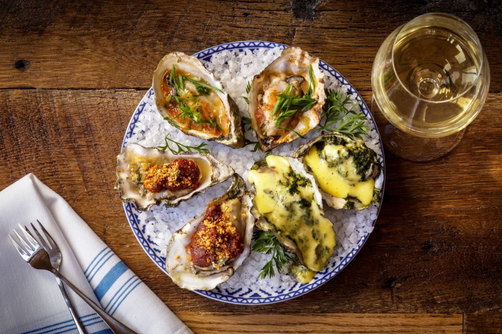 Grilled oysters with a glass of white wine at Salt Wood Kitchen & Oysterette