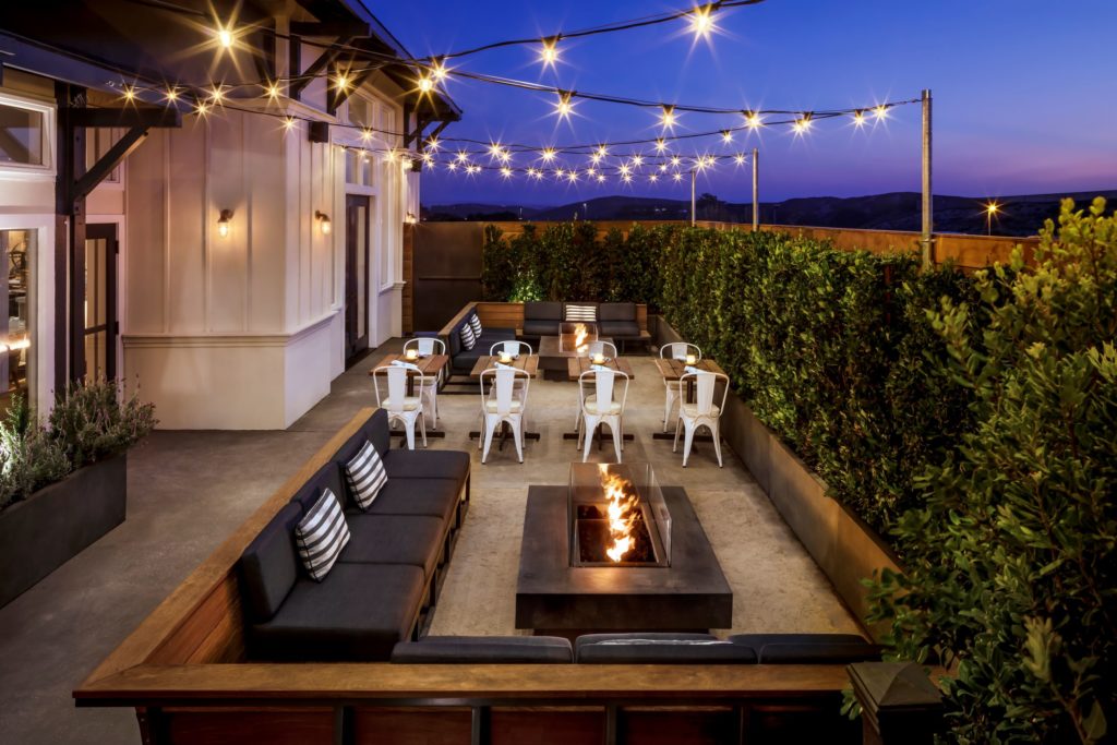 Salt Wood Kitchen & Oysterette outdoor patio at night with strings of lights and firepit