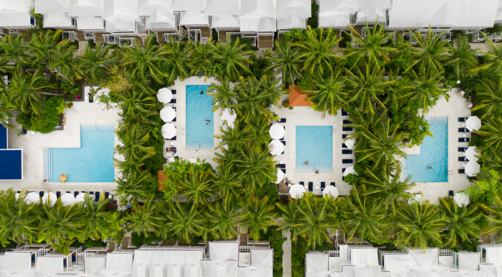 aerial view of four swimming pools surrounded by lush tropical foliage at Parrot Key Hotel & Villas