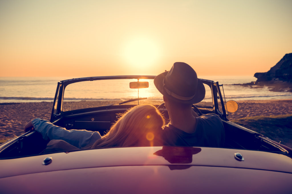 Couple watching the sunset in a convertible car