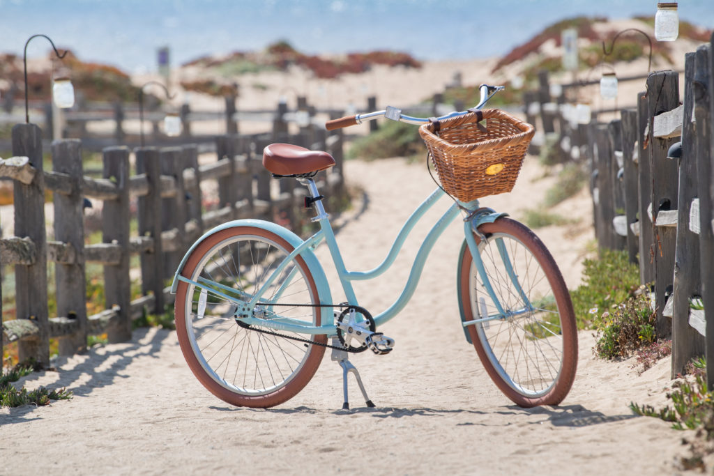 A bespoke bicycle with a basket parked in a sandy path at The Sanctuary Beach Resort