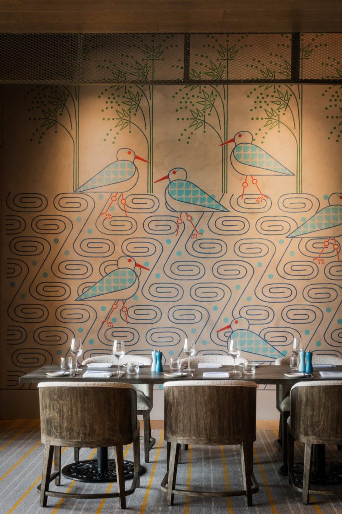 Dining table with place settings and mural wall at Hotel Nia