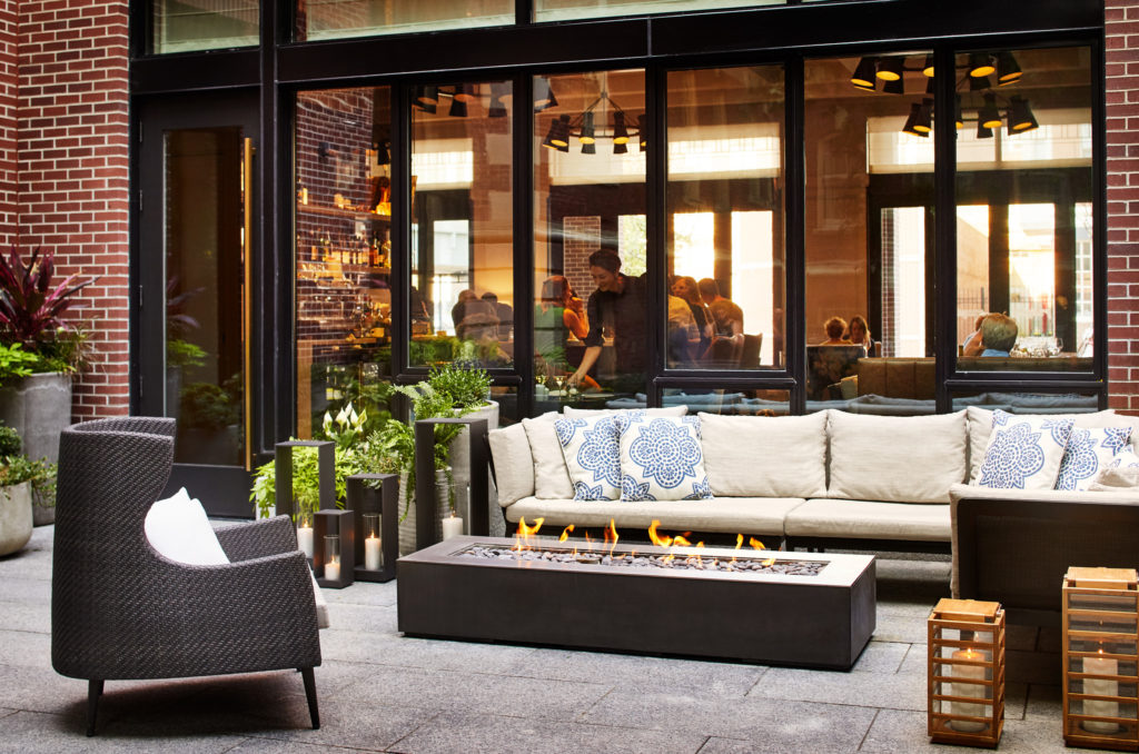 Outdoor courtyard with fire pit and lounge area outside Peregrine Restaurant at The Whitney Hotel