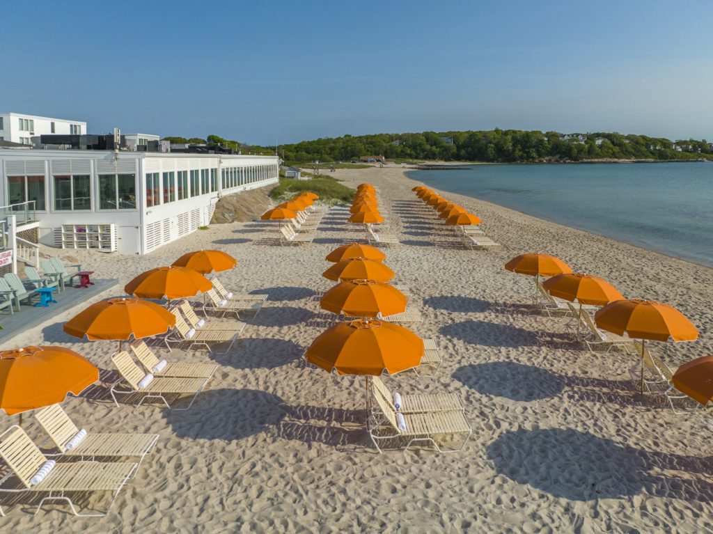 Lounge chairs and orange umbrellas along beach at Sea Crest Beach Hotel