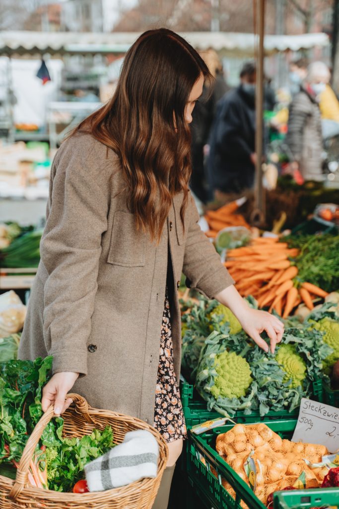 Woman holding a basket while shopping for vegetables at a farmers market