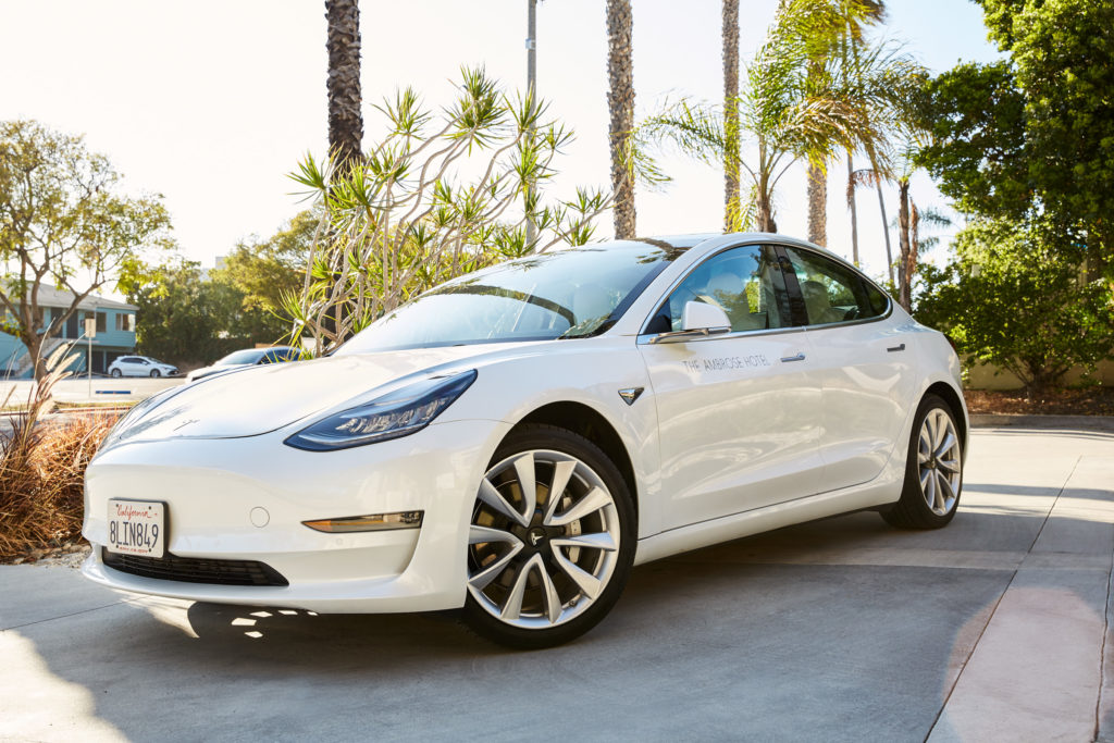 The Ambrose Hotel branded Tesla parked in front of palm trees