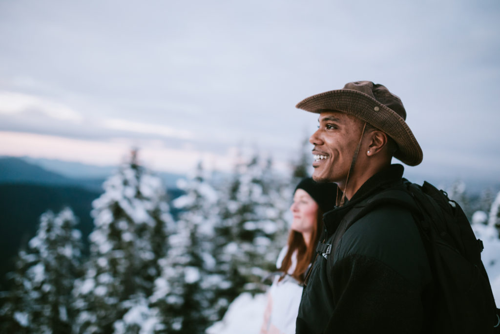 Two people hiking in the snow covered mountain areas of Washington state, USA pause to look at the beautiful view.  