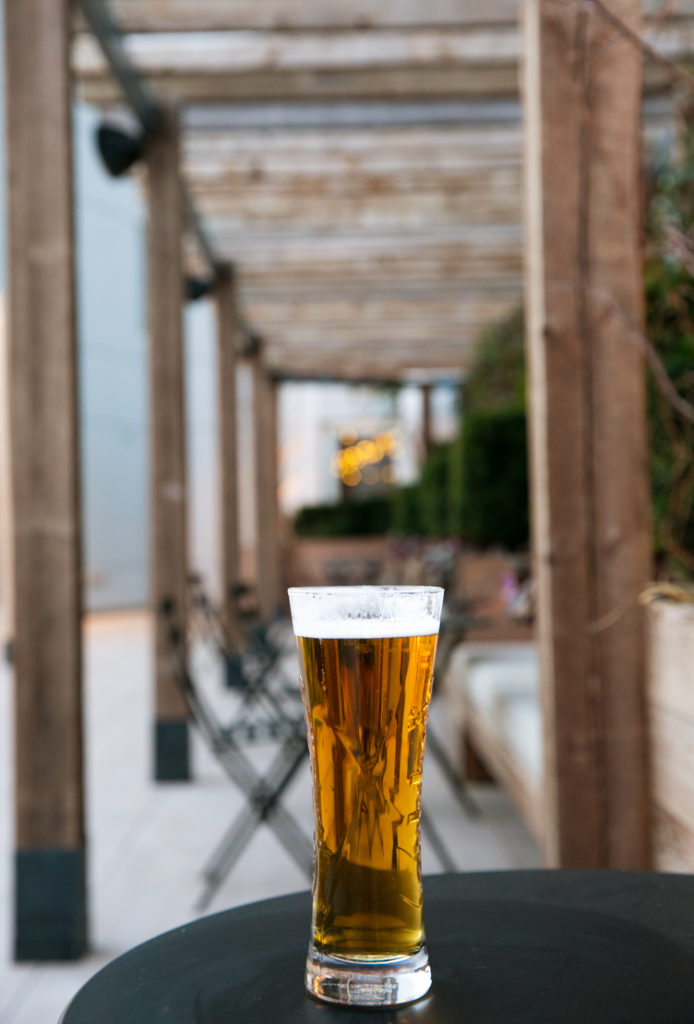 Tall glass of beer on a table at The Tillary Hotel Garden Bar in Brooklyn